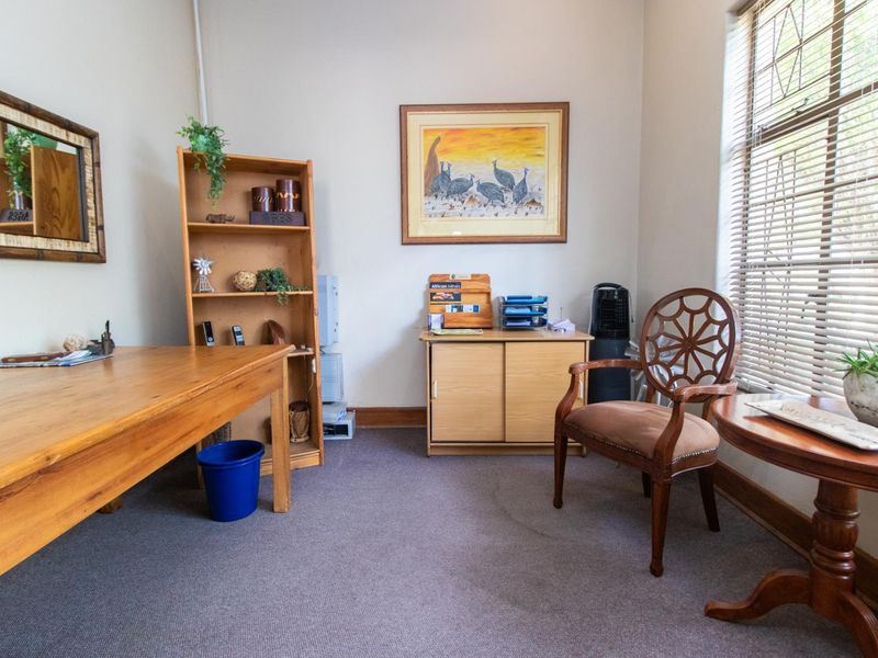 A functional office space featuring carpeted flooring and large windows with venetian blinds, providing a professional environment suitable for various business needs.