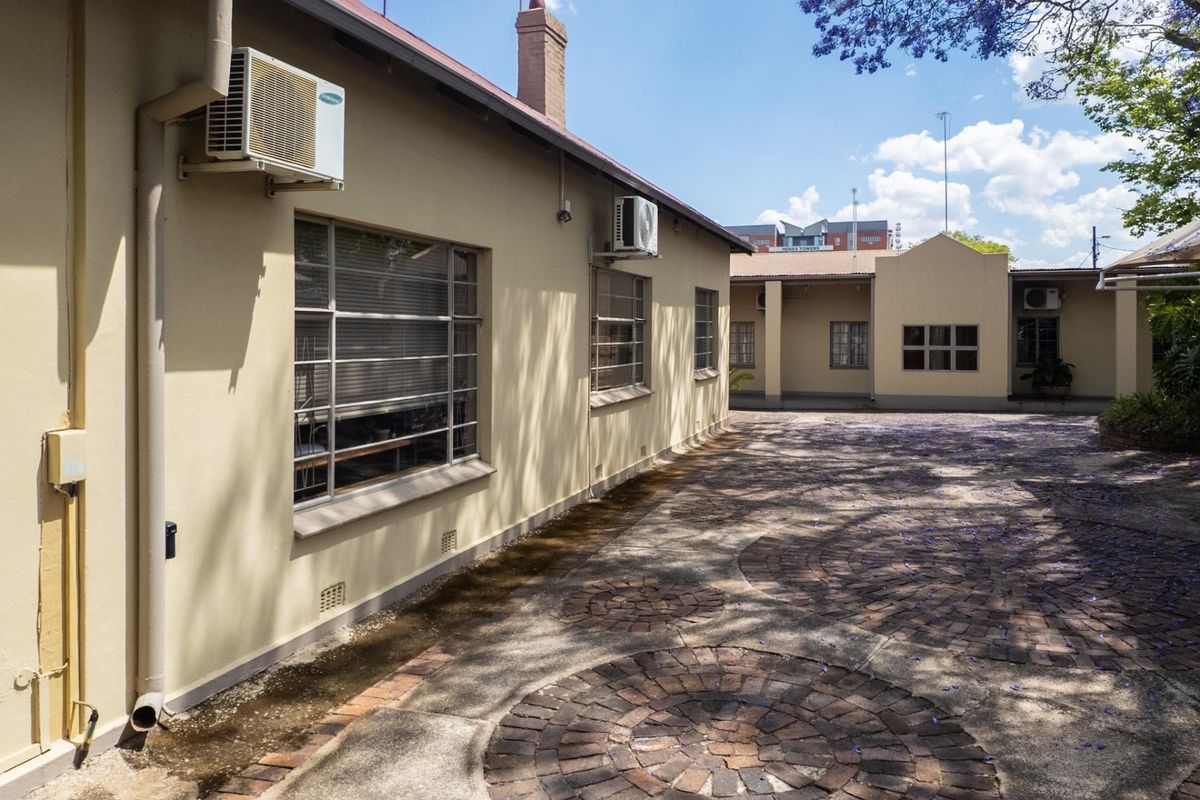 Rear exterior view of the office property featuring a paved courtyard, steel-framed windows, and wall-mounted air conditioning units.