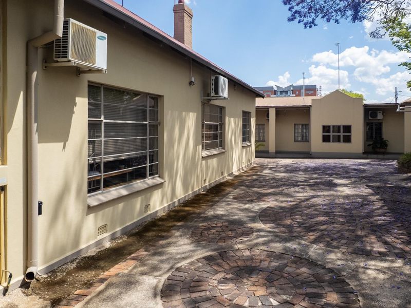 Rear exterior view of the office property featuring a paved courtyard, steel-framed windows, and wall-mounted air conditioning units.