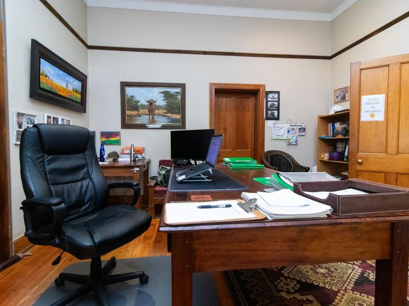 A functional office space featuring warm timber flooring, classic picture rails, and a solid timber door, providing a professional and traditional work environment.