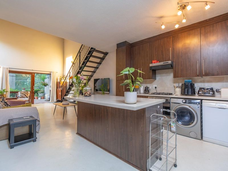 Spacious open-plan living area featuring a modern kitchen with built-in cabinetry, a central island, and direct access to an outdoor patio via sliding doors.