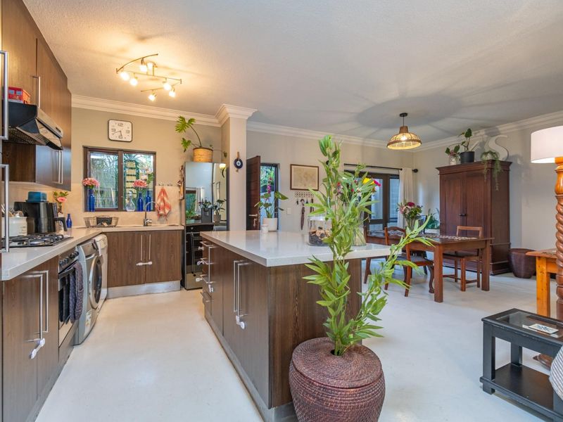 Open-plan kitchen and dining area featuring dark wood cabinetry, quartz countertops, a central island, and integrated appliances.