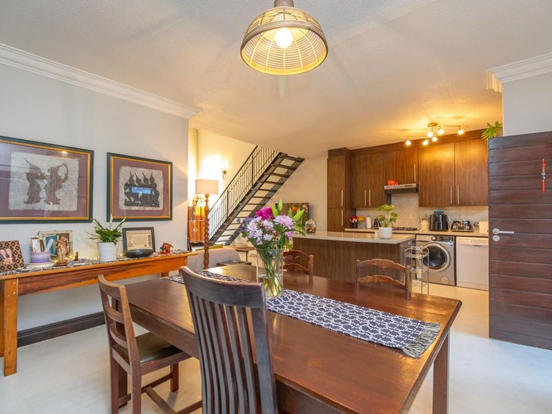 An open-plan living and dining area featuring a modern kitchen with built-in cabinetry and a staircase leading to the upper level.