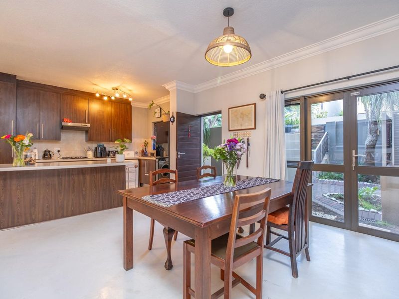 Open-plan kitchen and dining area featuring dark wood cabinetry, a functional kitchen island, and glass sliding doors providing direct access to the rear garden.