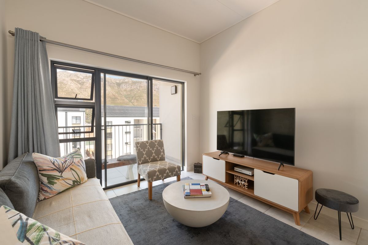 A bright and modern living room featuring tiled flooring and large sliding glass doors that provide access to a private balcony.
