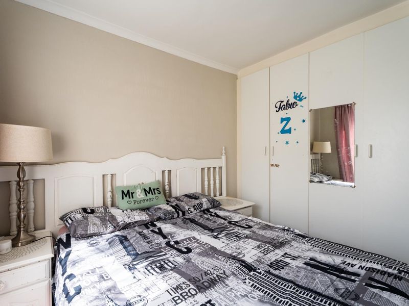 A bedroom featuring a built-in wardrobe with integrated mirror and neutral wall finishes.