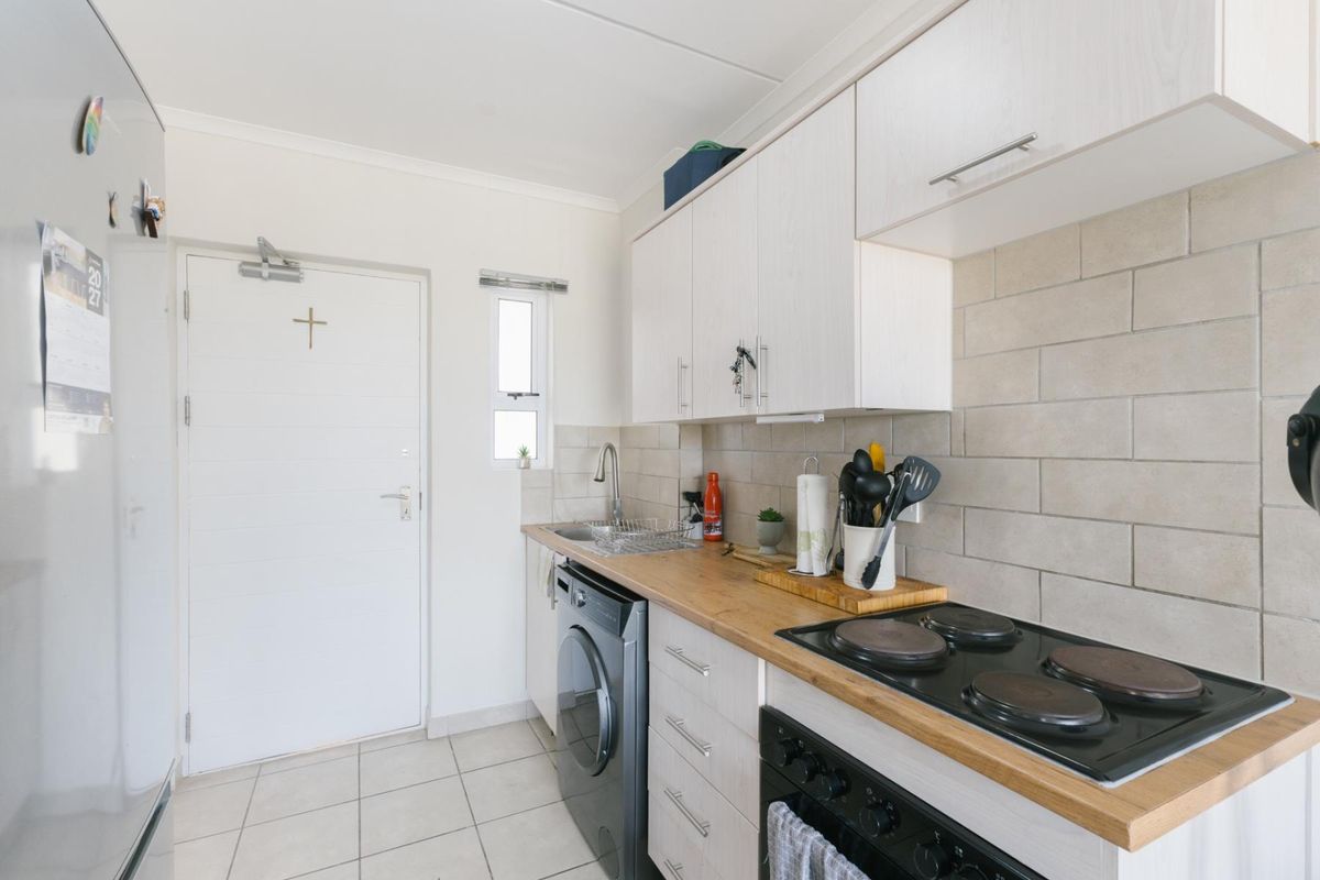 Compact kitchen featuring white cabinetry, wooden countertops, subway tile backsplash, and integrated electric hob and oven.