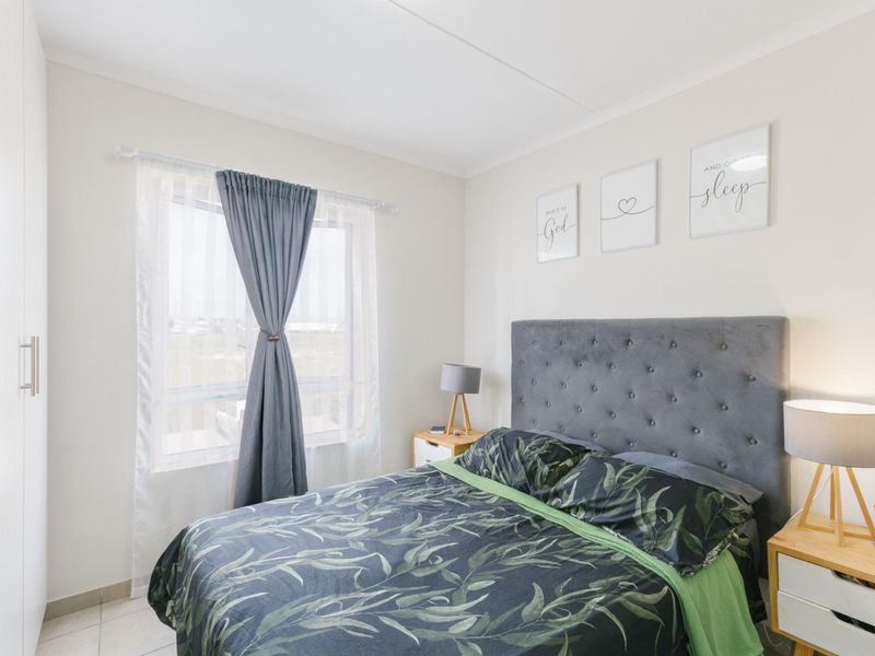 A well-maintained bedroom featuring neutral walls, tiled flooring, and a built-in wardrobe, offering a clean and comfortable living space.