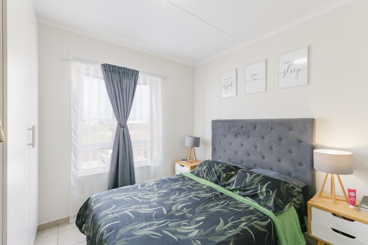 A well-maintained bedroom featuring neutral walls, tiled flooring, and a built-in wardrobe, offering a clean and comfortable living space.