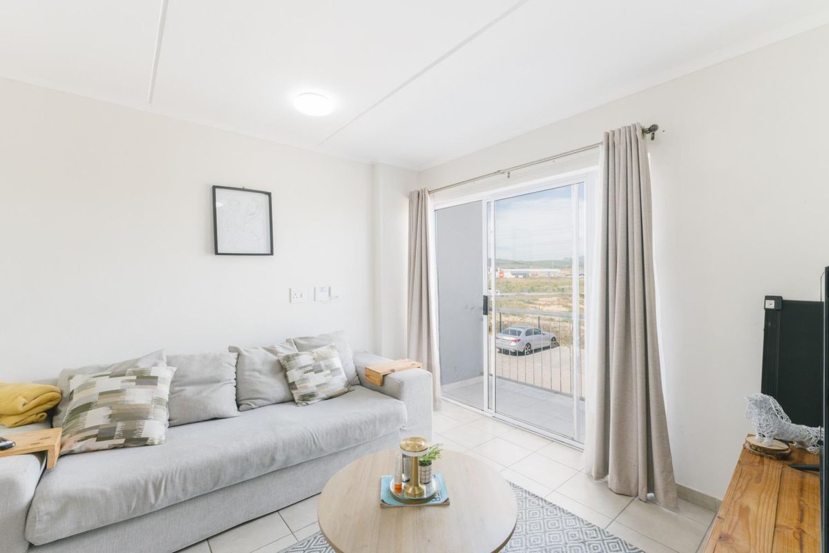 A bright living room featuring tiled flooring and a sliding glass door that provides access to an outdoor balcony area.