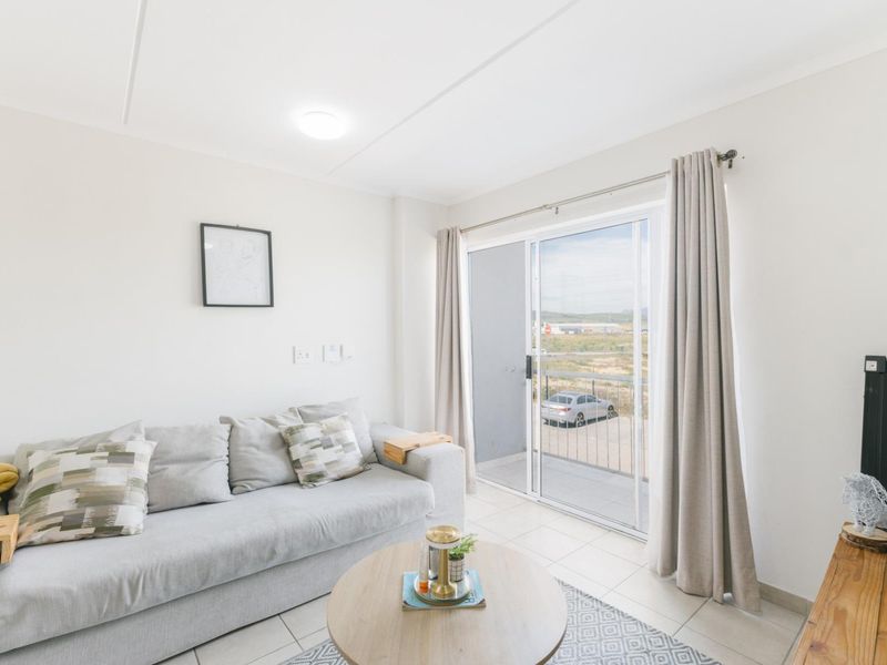 A bright living room featuring tiled flooring and a sliding glass door that provides access to an outdoor balcony area.