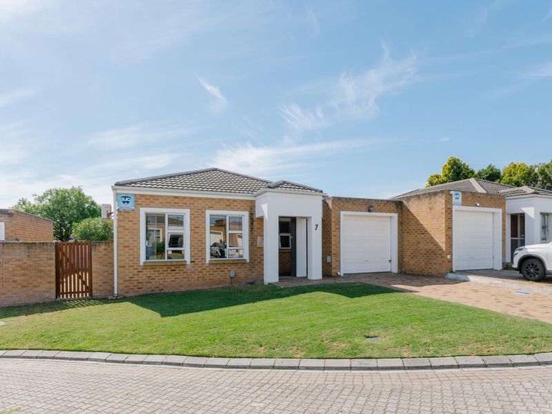Front elevation of a single-story townhouse featuring a brick facade, tiled roof, single garage, paved driveway, and a well-maintained front lawn.
