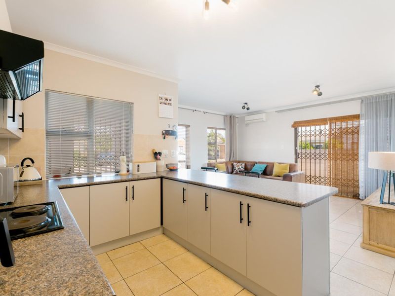 Open-plan kitchen and living area featuring modern cabinetry, tiled flooring, and sliding doors leading to the exterior.