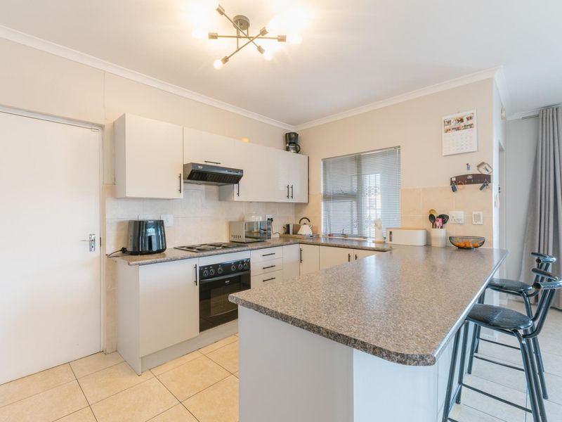Functional kitchen featuring granite countertops, built-in cabinetry, a breakfast bar, and tiled flooring, offering a practical layout for daily cooking and dining.