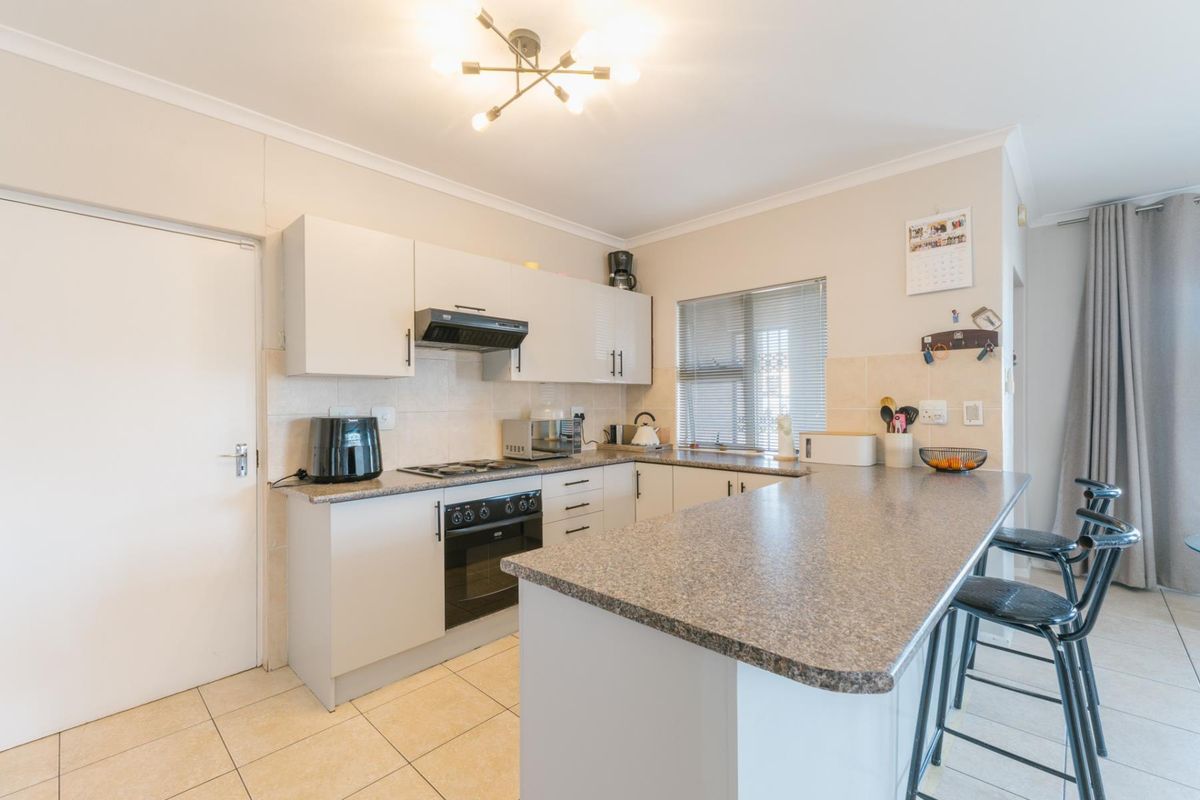 Functional kitchen featuring granite countertops, built-in cabinetry, a breakfast bar, and tiled flooring, offering a practical layout for daily cooking and dining.