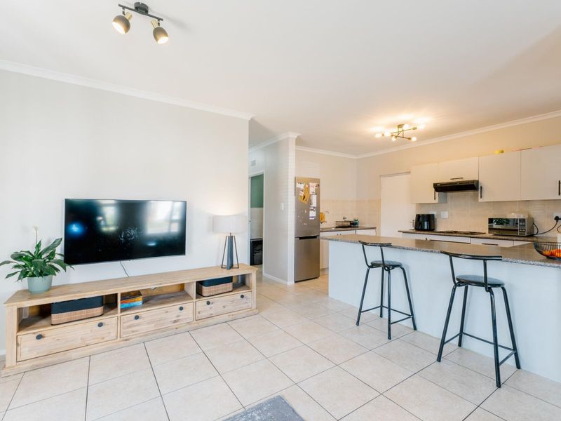 Open-plan living area featuring a modern kitchen with granite countertops, breakfast bar, and tiled flooring throughout, creating a functional and cohesive living space.