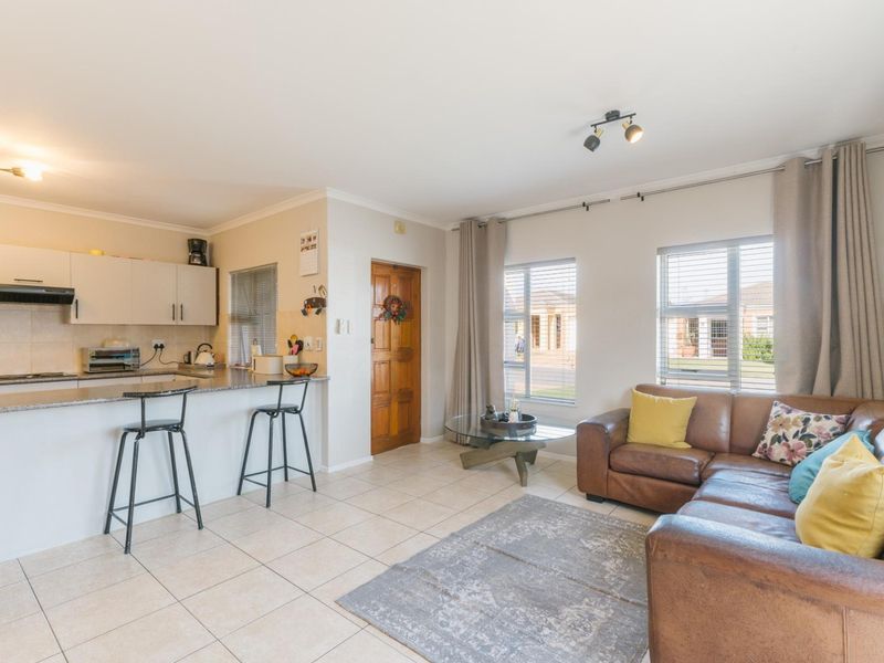 Open-plan living area featuring a kitchen with granite countertops and built-in cabinetry, seamlessly flowing into a comfortable lounge space with tiled flooring.