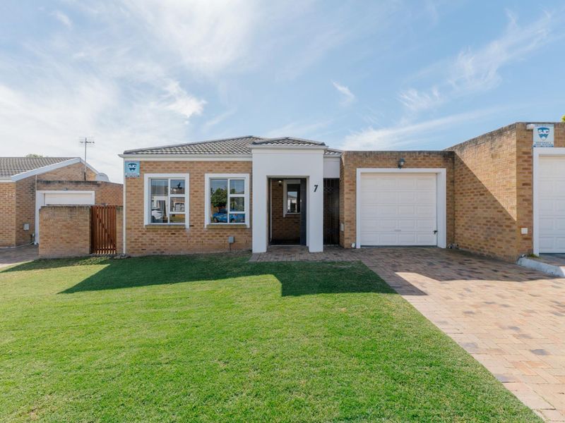 Front elevation of a brick townhouse featuring a paved driveway, single garage, and a well-maintained front lawn.