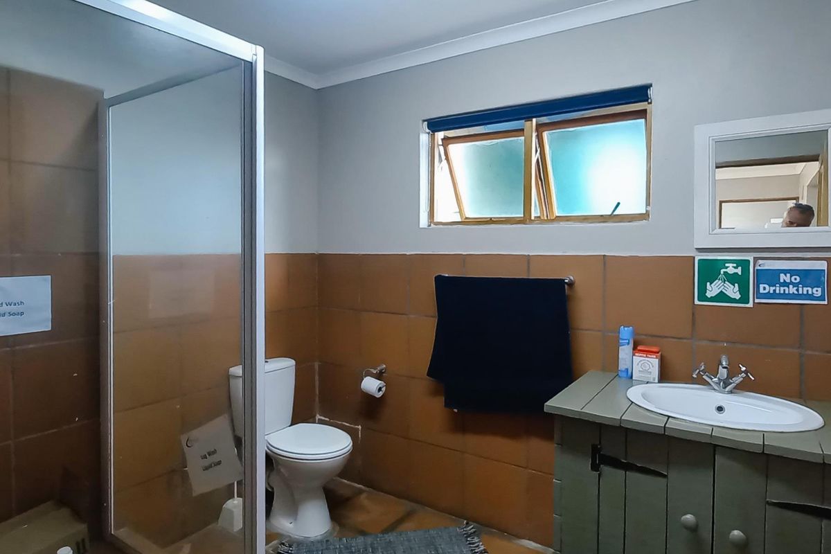 A functional bathroom featuring a shower enclosure, toilet, and vanity basin with tiled wall finishes and a top-hung window.