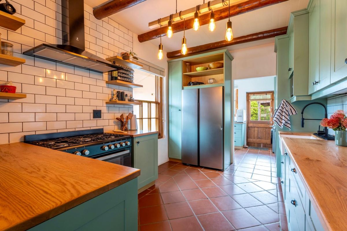 A charming, well-maintained kitchen featuring exposed timber beams, subway tile backsplash, wooden countertops, and custom cabinetry with a classic farmhouse aesthetic.