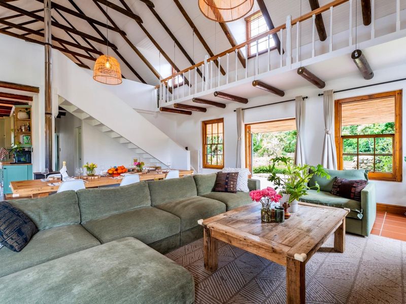 Spacious open-plan living and dining area featuring high vaulted ceilings with exposed timber trusses, a mezzanine level, and direct access to the garden.