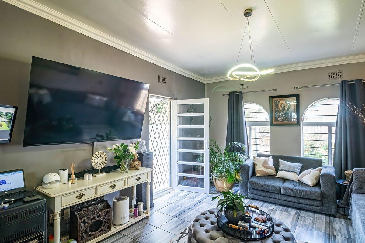 A well-maintained living room featuring tiled flooring, crown molding, and arched windows, providing a bright and comfortable space for relaxation.