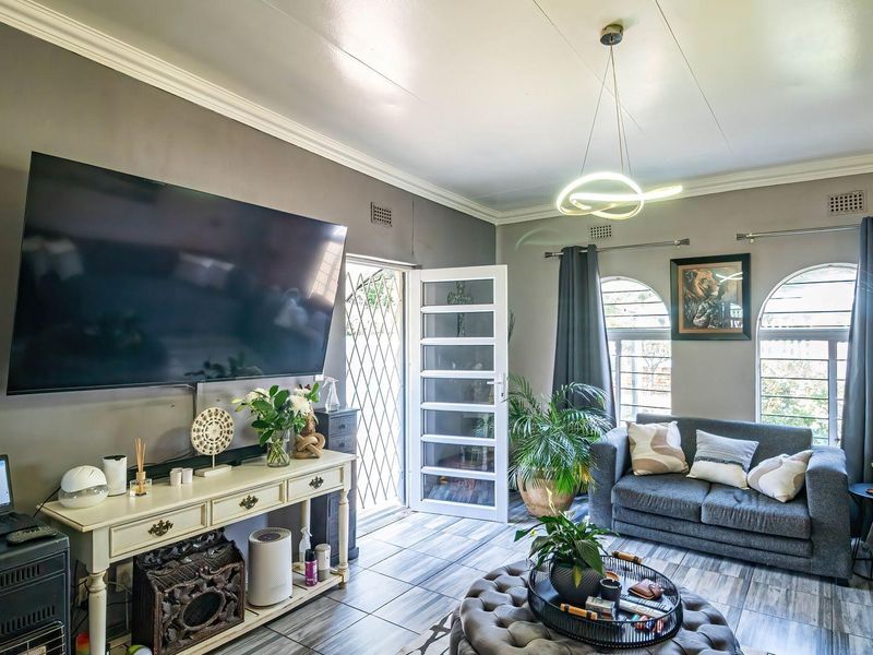 A well-maintained living room featuring tiled flooring, crown molding, and arched windows, providing a bright and comfortable space for relaxation.