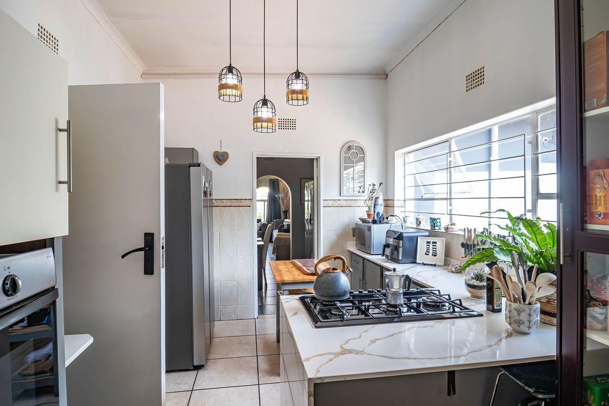 A functional kitchen featuring stone countertops, a gas hob, built-in oven, and tiled finishes, offering a clean and practical workspace.