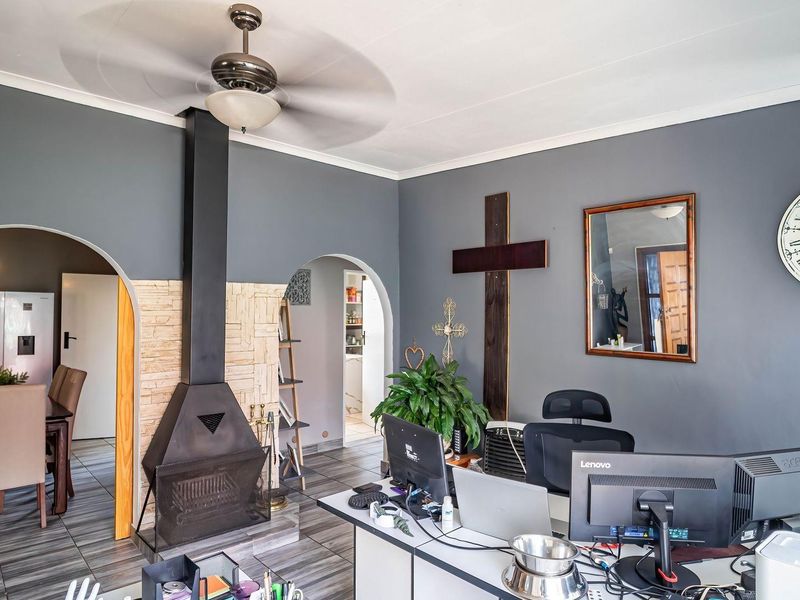Living area featuring a prominent freestanding fireplace with stone surround, tiled flooring, and arched doorways leading to adjacent spaces.