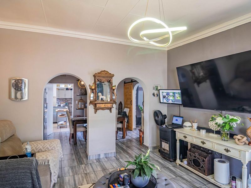 A well-maintained living room featuring tiled flooring, decorative archways, and modern lighting, providing a comfortable and connected living space.
