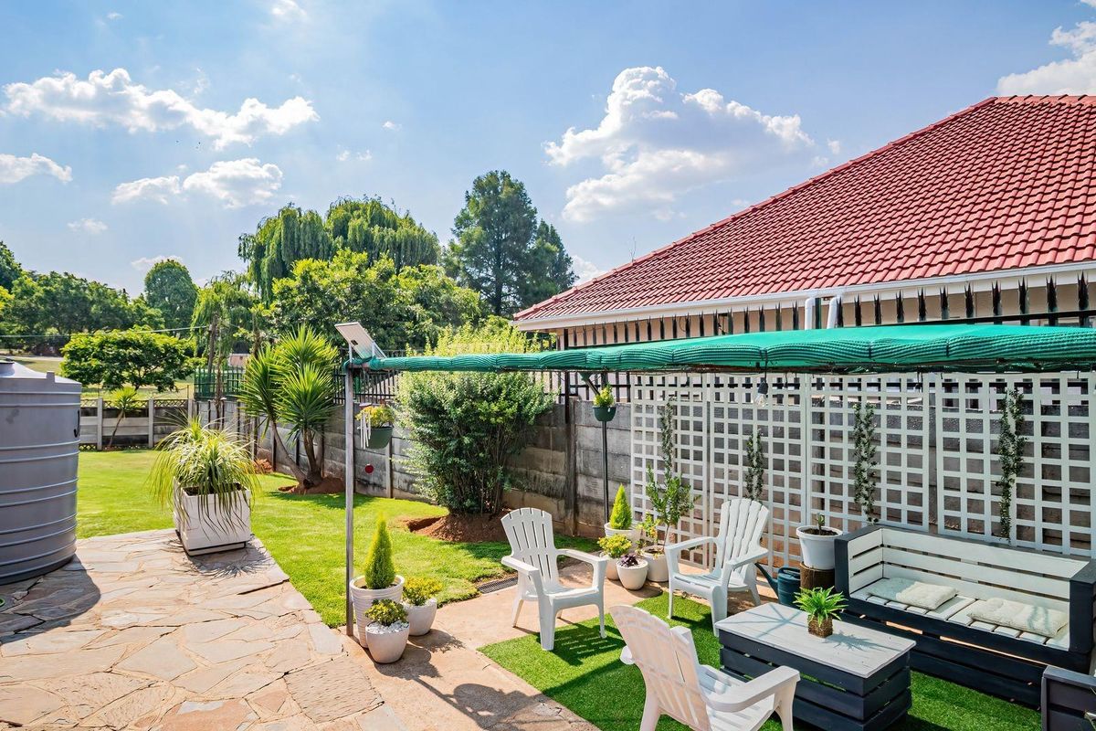 A well-maintained rear garden featuring stone paving, a water storage tank, and a shaded patio area with a lattice screen boundary.