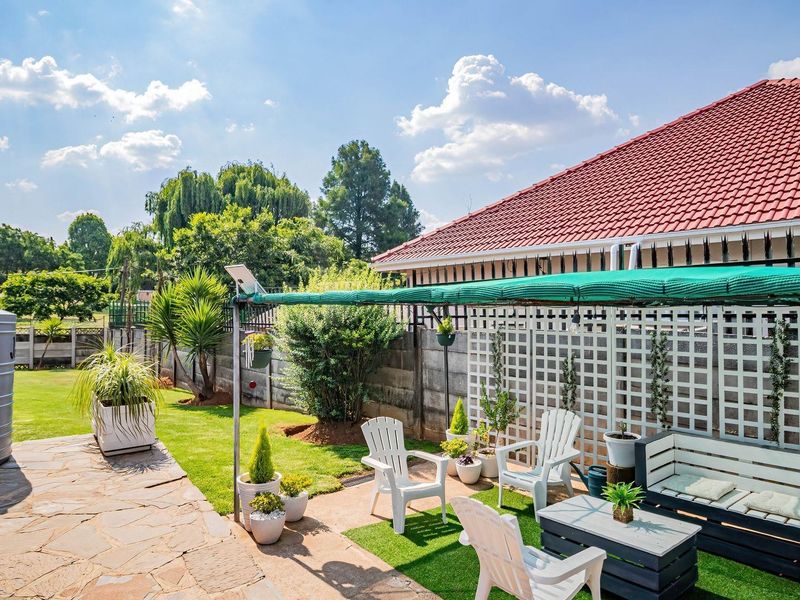 A well-maintained rear garden featuring stone paving, a water storage tank, and a shaded patio area with a lattice screen boundary.