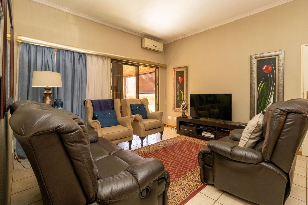 A comfortable living room featuring tiled flooring, a wall-mounted air conditioning unit, and sliding glass doors providing access to the outdoor area.