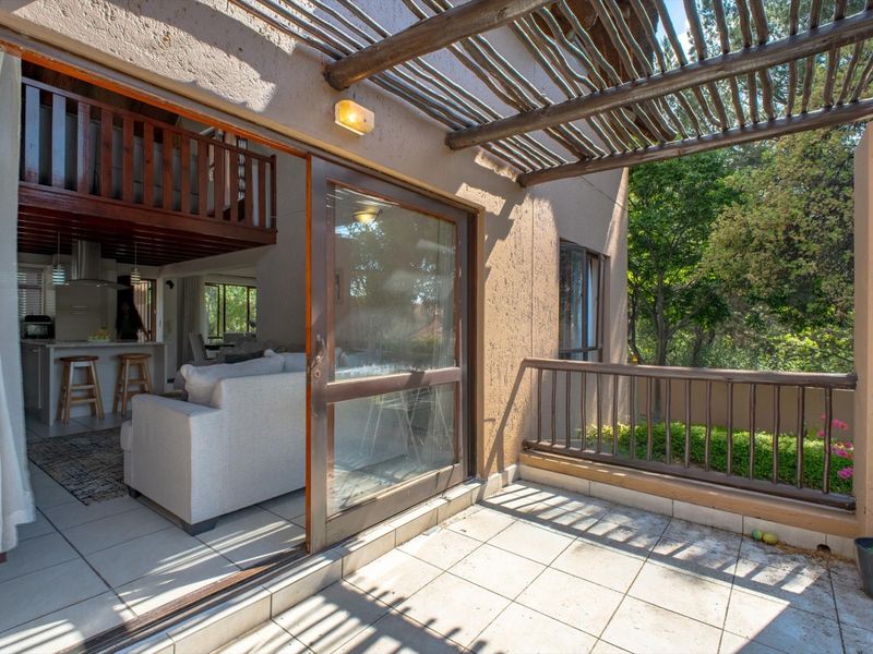 A covered balcony featuring a timber pergola, tiled flooring, and a metal balustrade, providing a seamless transition to the interior living space.