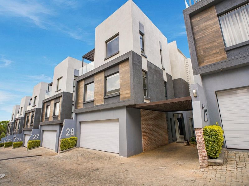 Modern multi-level townhouse complex featuring contemporary architectural design, automated garages, paved driveways, and stylish timber-look facade accents.