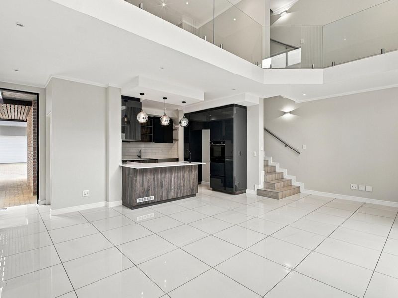 Spacious open-plan living area featuring a modern kitchen with built-in cabinetry, a central island, and a sleek staircase with glass balustrades.
