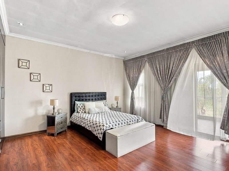Spacious bedroom featuring warm laminate flooring, built-in cupboards, and large sliding glass doors that provide access to an outdoor area.