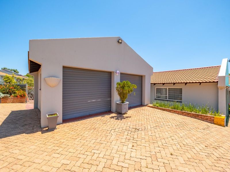 A well-maintained double garage with a paved driveway and brick planter, featuring a clean exterior facade and tiled roof.