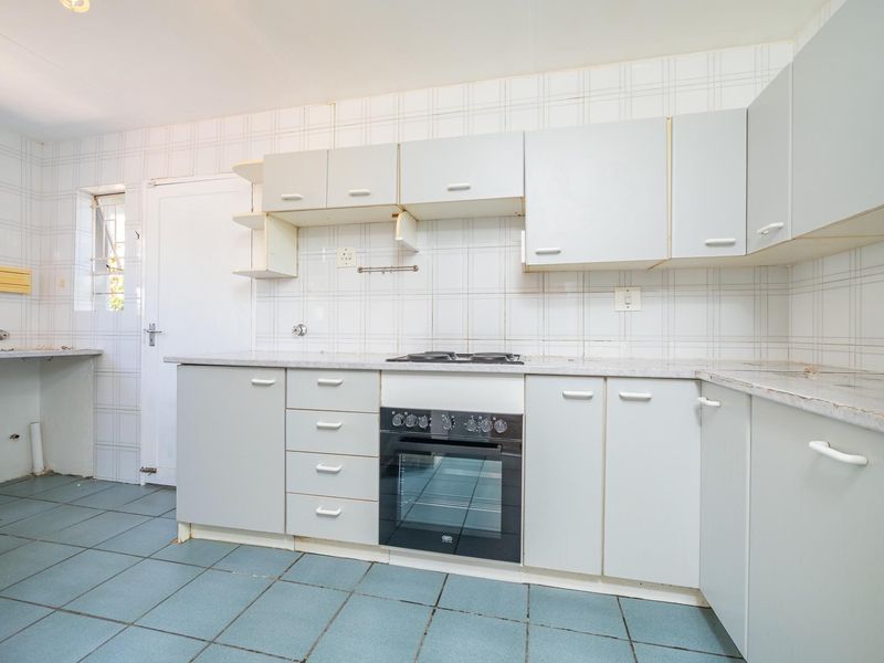 A functional kitchen featuring built-in cabinetry, a built-in oven with hob, and tiled splashbacks, offering a blank canvas for modern renovation.