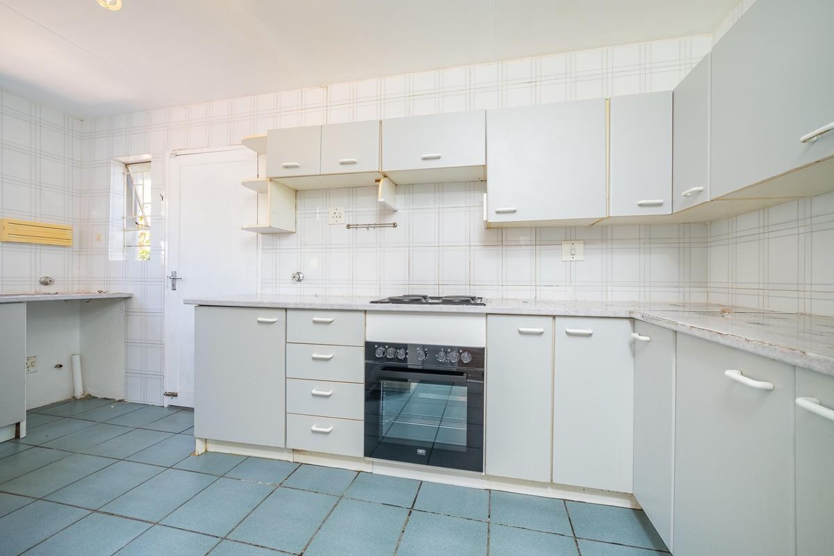 A functional kitchen featuring built-in cabinetry, a built-in oven with hob, and tiled splashbacks, offering a blank canvas for modern renovation.