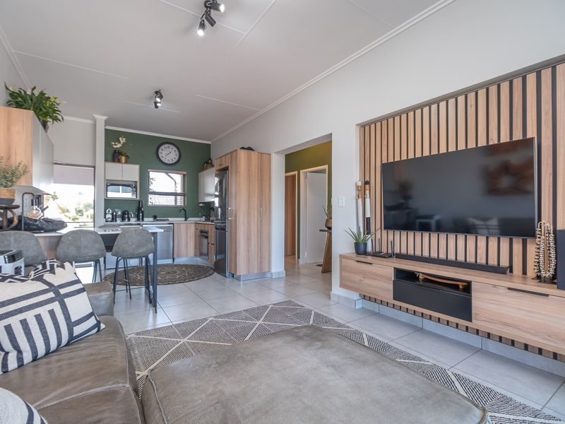 Modern open-plan living area featuring a contemporary kitchen with built-in cabinetry and a stylish media wall with timber slat detailing.