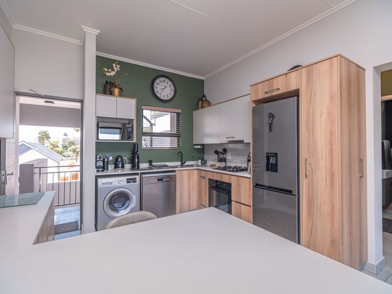 Modern kitchen featuring wood-look and white cabinetry, stone countertops, integrated appliances, and a gas hob, with direct access to a balcony.