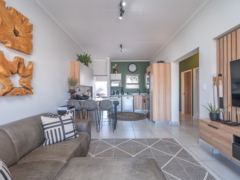 A modern open-plan living and kitchen area featuring tiled floors, contemporary cabinetry, and a stylish slatted wood feature wall.
