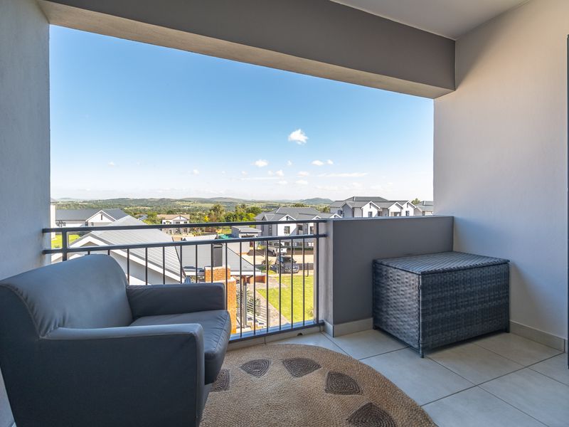 A covered balcony featuring tiled flooring and a metal balustrade, offering elevated views of the surrounding residential estate.