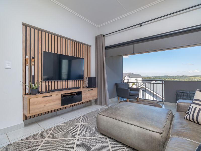 Modern living room featuring a stylish slatted timber feature wall, floating media console, and seamless access to a balcony with scenic views.
