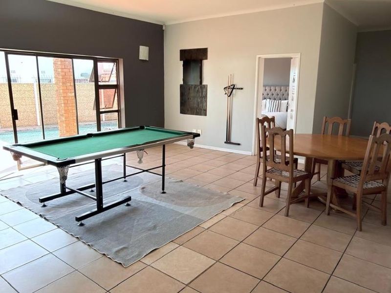 Spacious living area featuring tiled flooring and large sliding glass doors providing direct access to the outdoor pool area.
