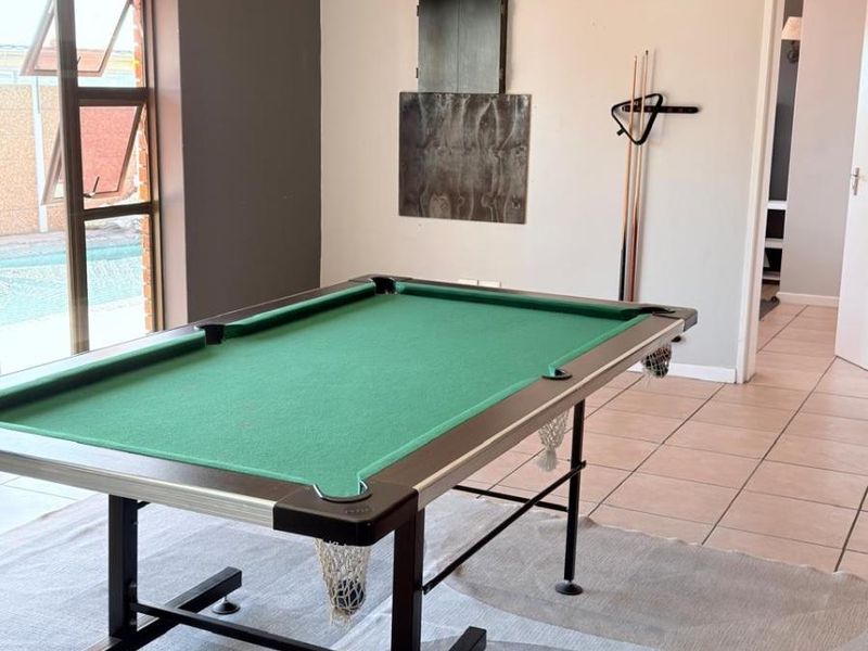 A versatile living area featuring tiled flooring, large windows with pool views, and neutral wall finishes, suitable for a lounge or entertainment space.
