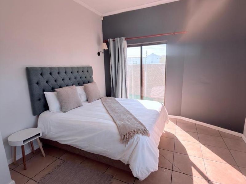 A well-lit bedroom featuring tiled flooring, a coved ceiling, and a sliding glass door providing access to the exterior.