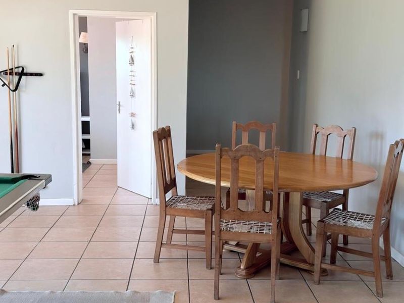 A dining area featuring neutral wall paint and tiled flooring, providing a functional space for meals with access to adjacent rooms.