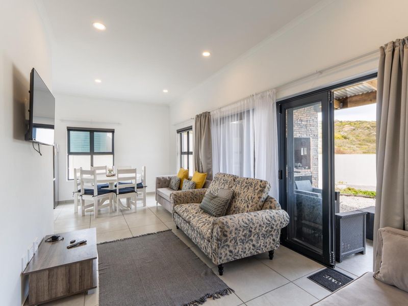 Bright open-plan living and dining area featuring tiled floors, recessed lighting, and large sliding doors providing seamless access to the outdoor patio space.